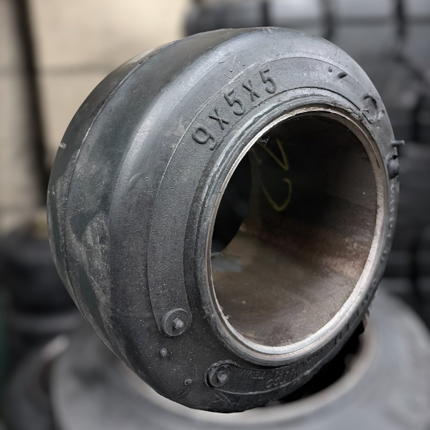 Close-up of a 9x5x5 forklift tire and metal bearing with visible branding and specifications.