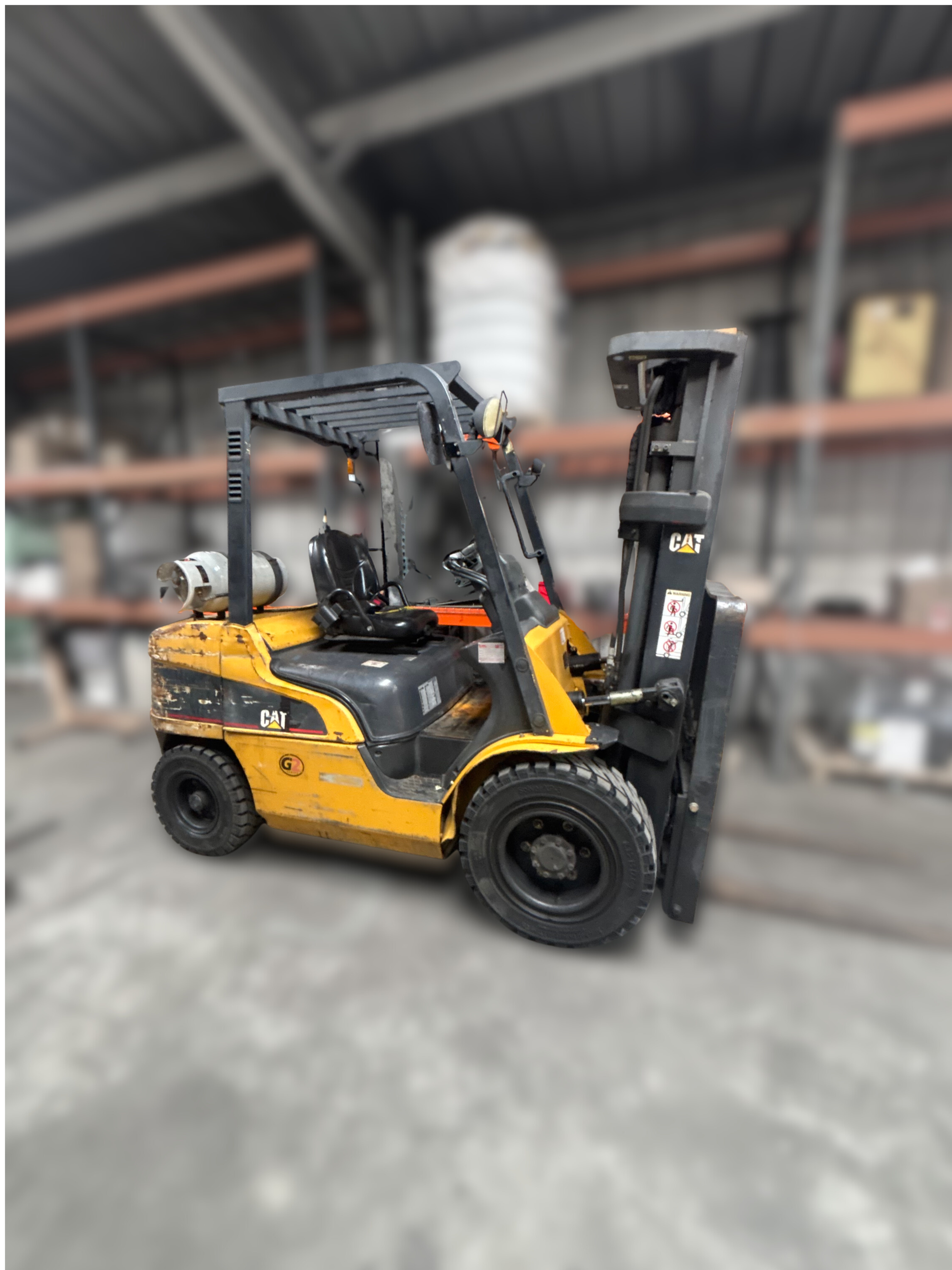 Yellow and black Caterpillar p6000 pneumatic forklift in a warehouse setting