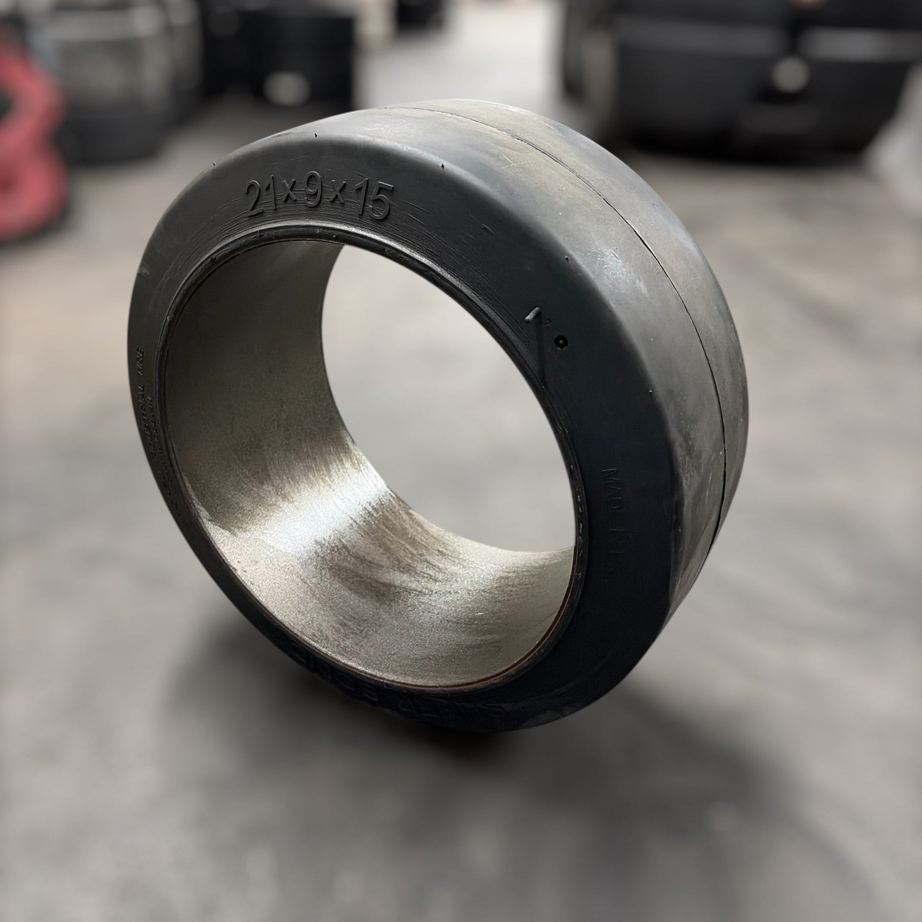 Metallic forklift tire bearing on a gray surface with blurred background