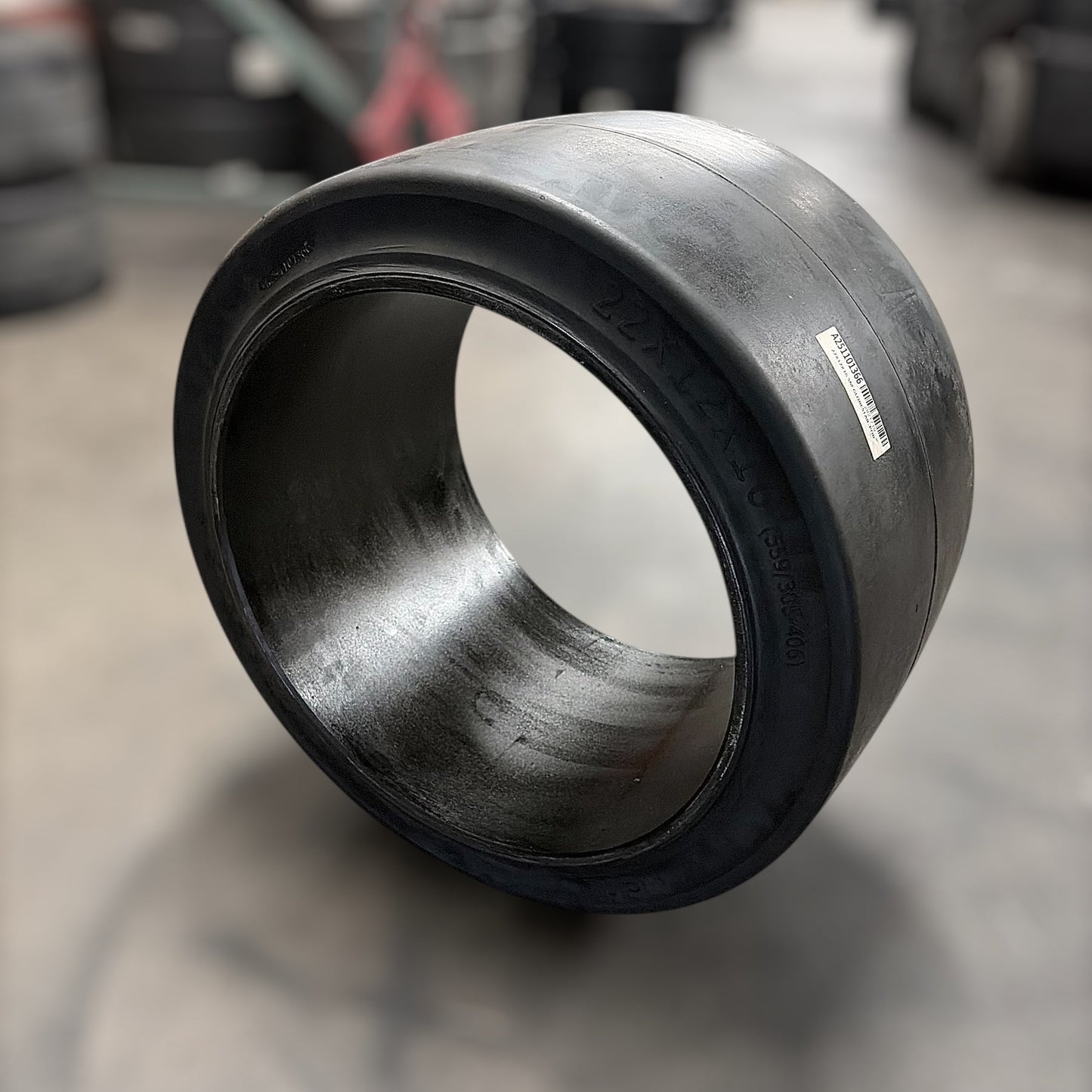 Black forklift rubber bushing on a concrete floor with tires in the background